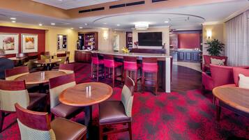 A hotel lobby with round tables, bar area, and seating.