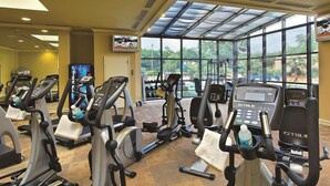 A gym with various cardio machines, a television screen, and large windows offering a view of the outdoors. - Doubletree by Hilton Columbia, SC (Columbia)