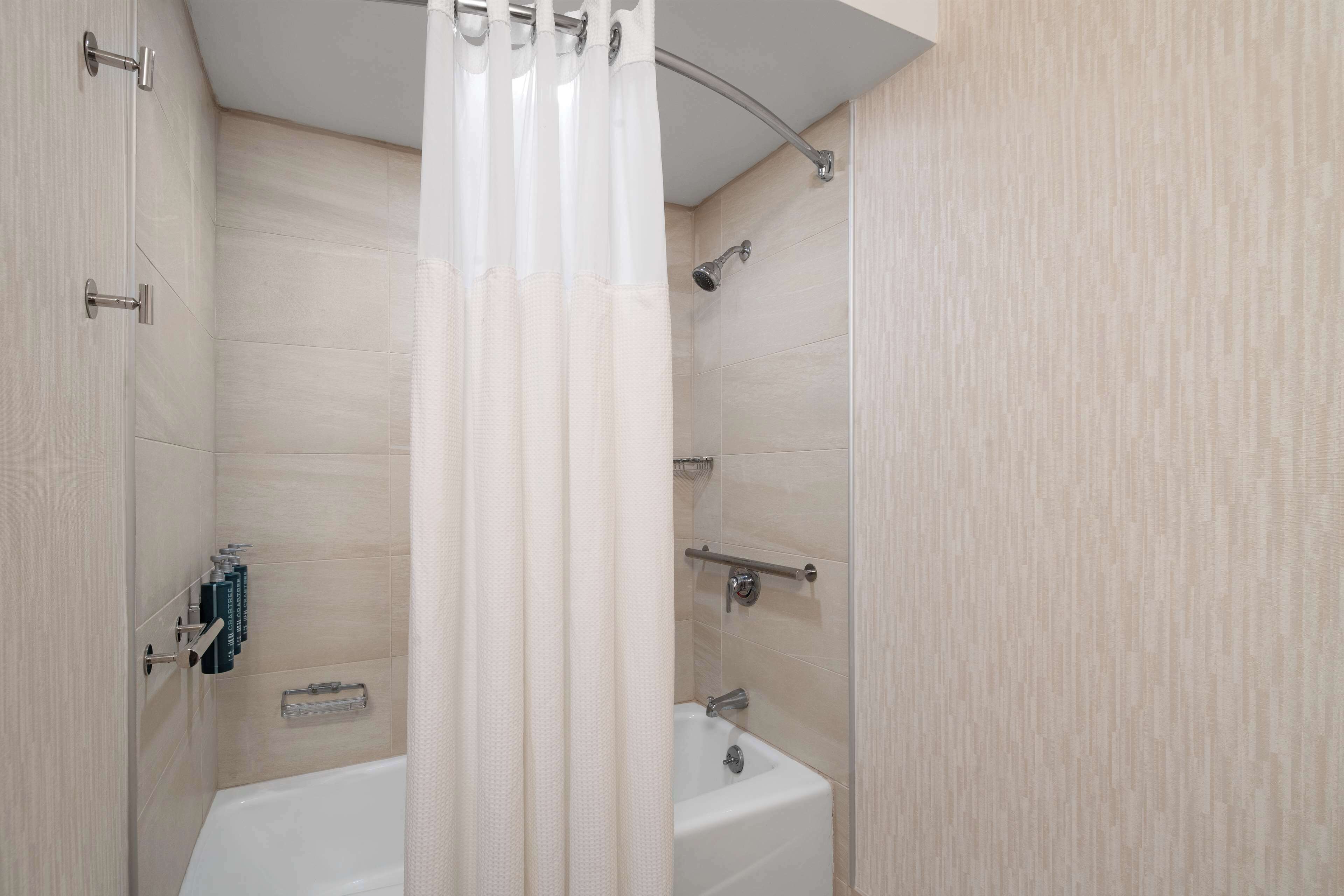 A modern bathroom with a bathtub, shower, and toilet.