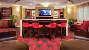 A bar area with a television, red bar stools, and a red carpeted floor. - Doubletree by Hilton Columbia, SC (Columbia)