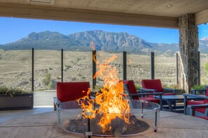 A fire pit with a mountain view, red chairs, and a stone pillar. - Ridgeline Hotel at Yellowstone, an Ascend Collection Hotel (Gardiner)