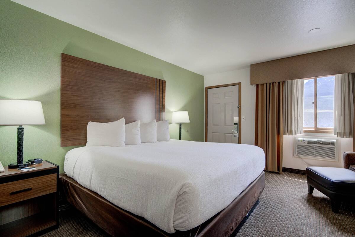 A hotel room with a large bed, two bedside tables with lamps, a desk, and a chair.