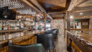 Un bar avec un comptoir en bois, des tabourets noirs et un jeu de roue à faire tourner.