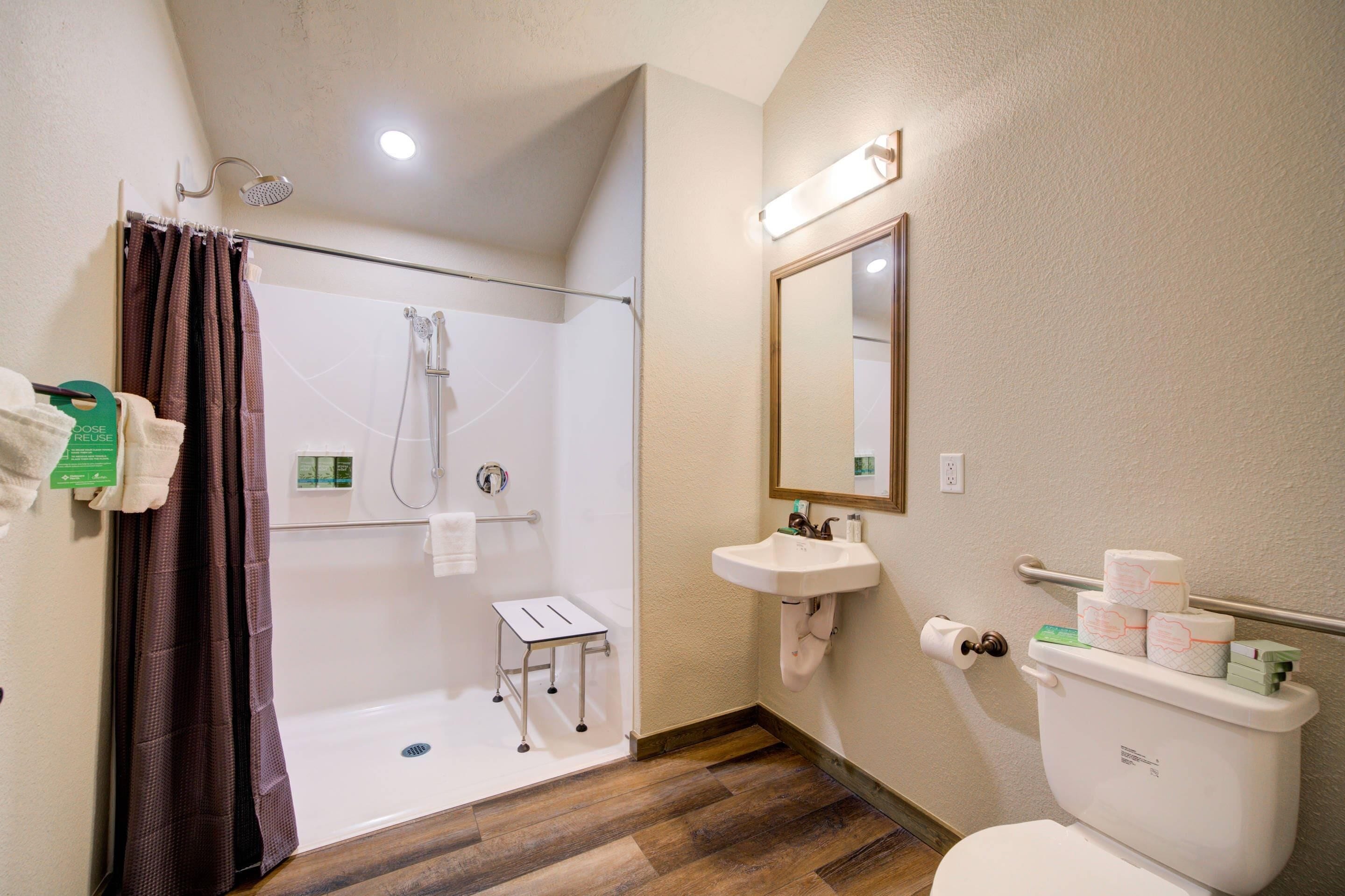 Ein Badezimmer mit Dusche, Toilette, Waschbecken und Spiegel.