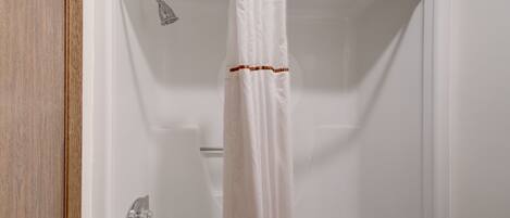 A shower with a white curtain and a chrome showerhead.