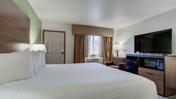 Habitación de hotel con una cama grande, un escritorio con microondas, un televisor y una puerta.