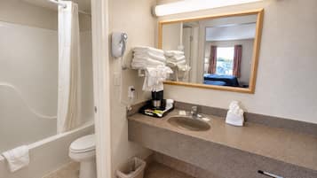 Un baño con ducha, inodoro, lavamanos y espejo.
