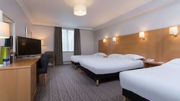 Habitación de hotel con dos camas, un escritorio con computadora, una silla y un televisor.