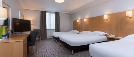 Une chambre d’hôtel avec deux lits, un bureau avec un ordinateur, une chaise et un téléviseur.