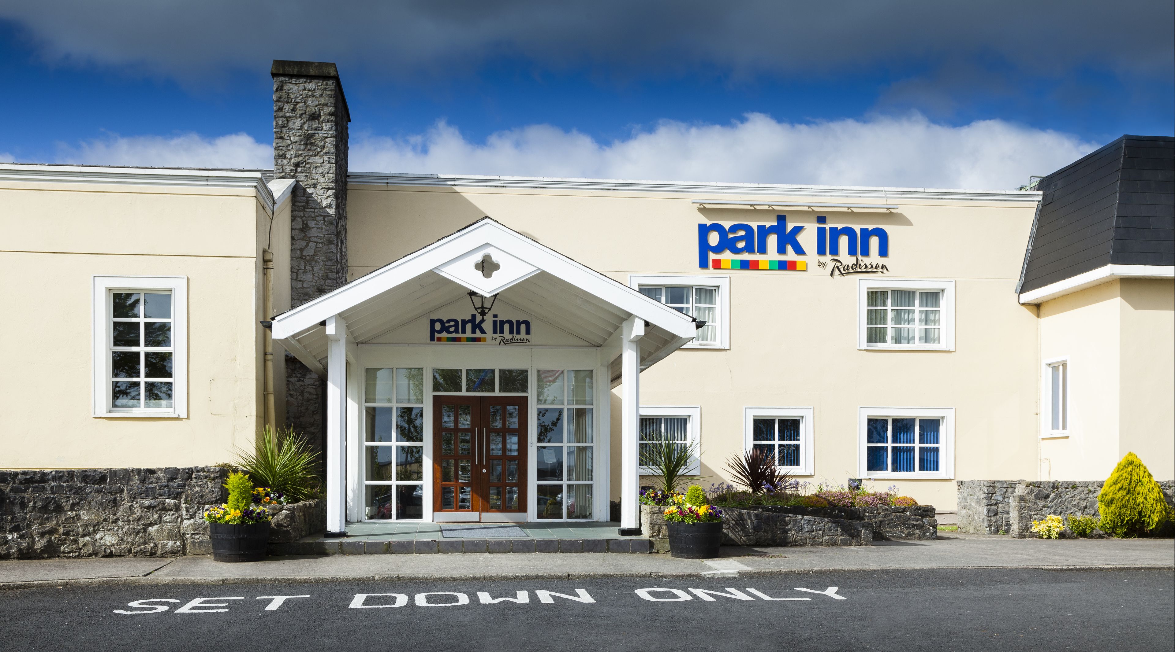 A park inn with a stone chimney, a set down only sign, and a signboard with the name 'park inn by Radisson'.