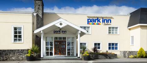 A park inn with a stone chimney, a set down only sign, and a signboard with the name 'park inn by Radisson'.