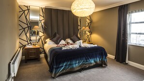 A hotel room with a large bed, two bedside lamps, a modern chandelier, and a view of the city through a window. - Park Inn by Radisson Shannon Airport (Shannon)