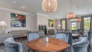 A hotel lobby with a round wooden table, grey upholstered chairs, and large abstract paintings on the walls. - Park Inn by Radisson Shannon Airport (Shannon)