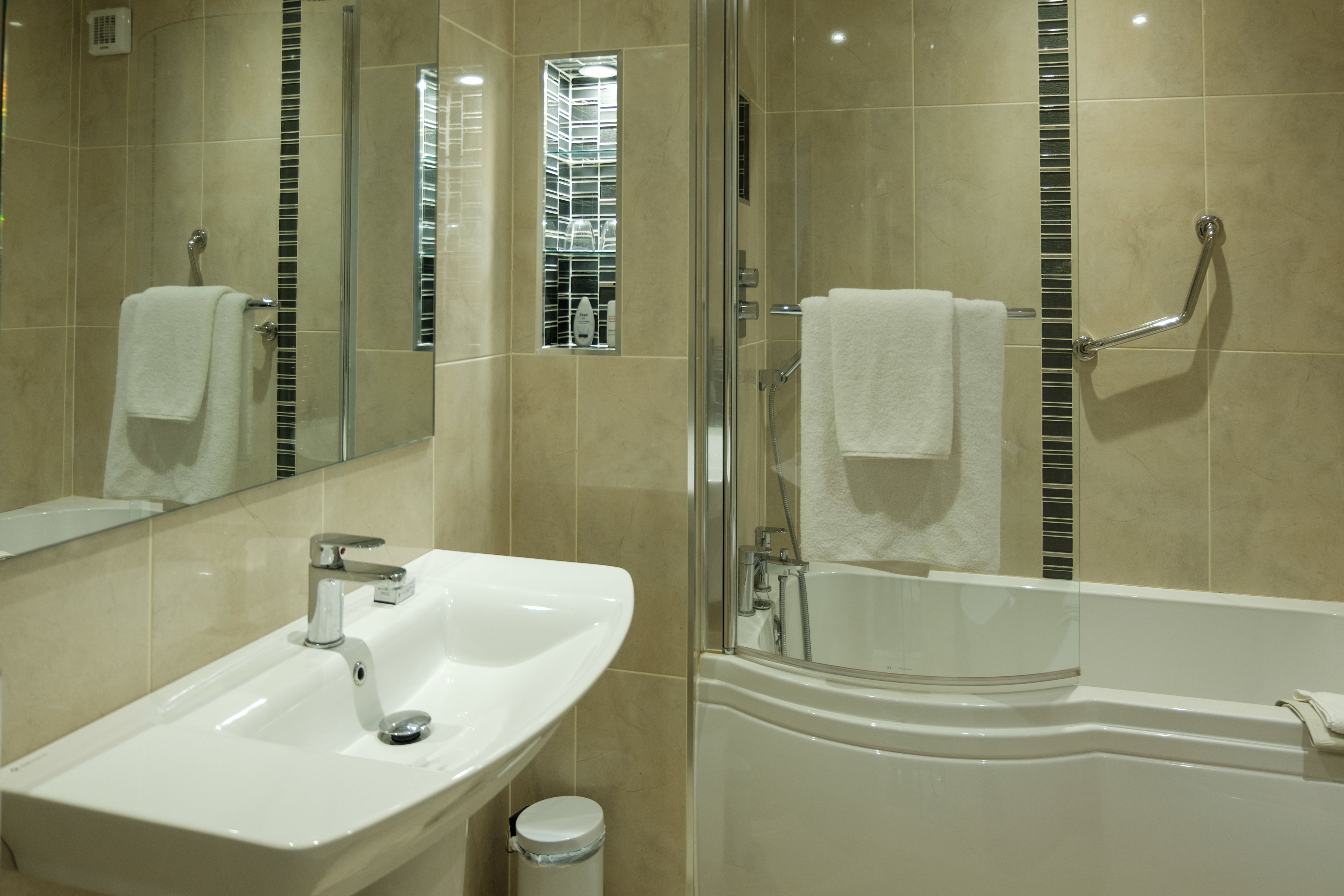 A bathroom with a sink, mirror, and bathtub.
