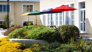 A building with a garden area featuring a variety of plants and three umbrellas. - Park Inn by Radisson Shannon Airport (Shannon)