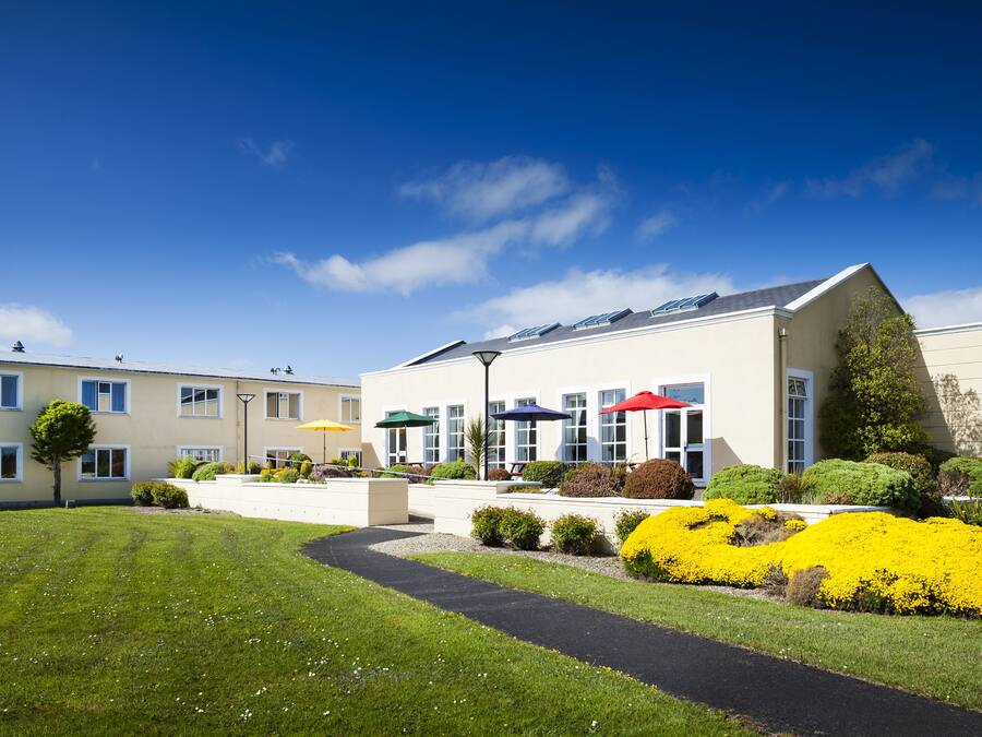 A modern hotel with a well-maintained lawn, a pathway, and colorful umbrellas.