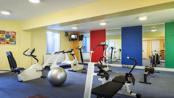 A gym with exercise equipment, a large mirror, and a colorful wall.