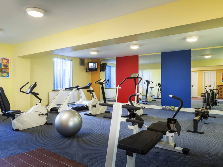 A gym with exercise equipment, a large mirror, and a colorful wall.