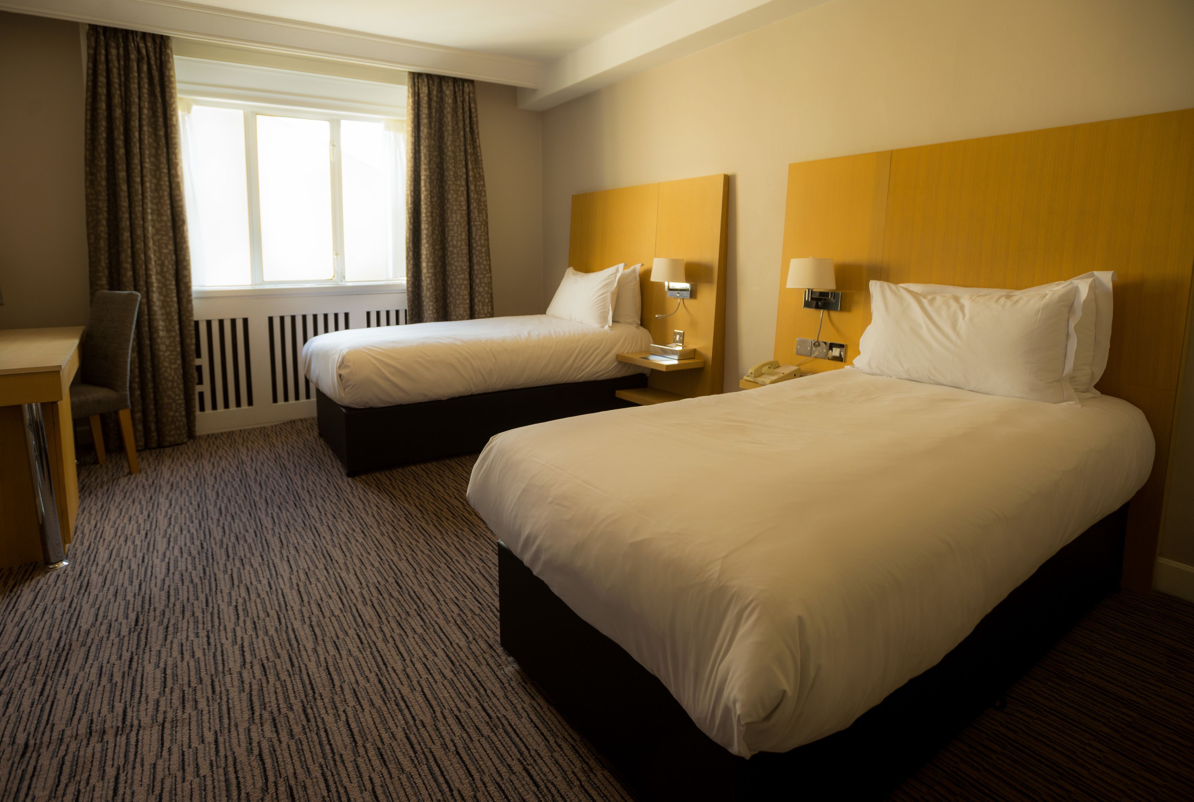 Habitación de hotel con dos camas, un escritorio y una silla.