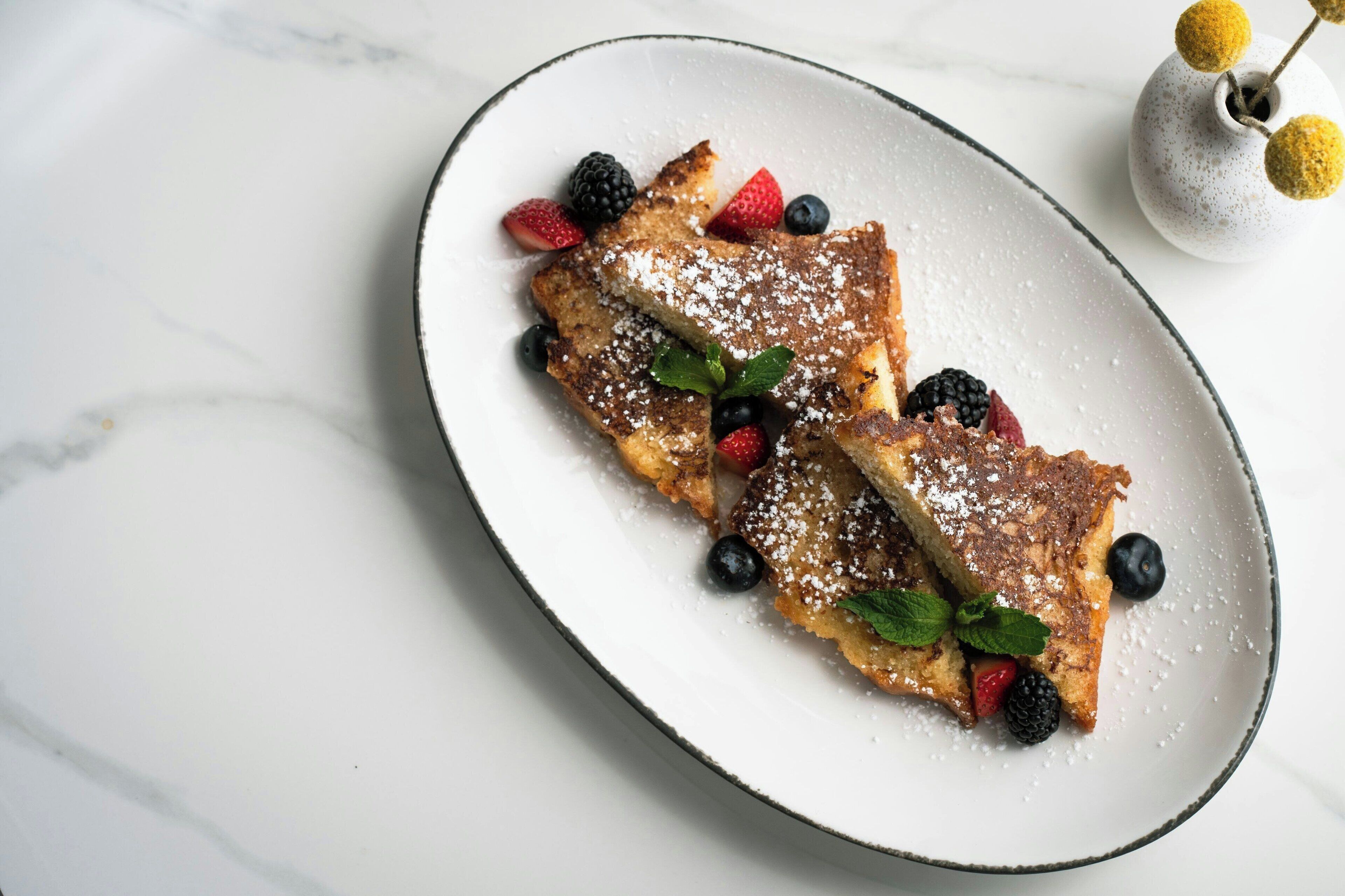 Ein Teller French Toast mit Beeren und Puderzucker.