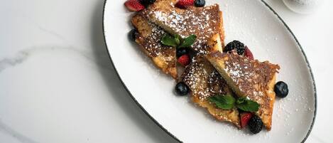 Ein Teller French Toast mit Beeren und Puderzucker.