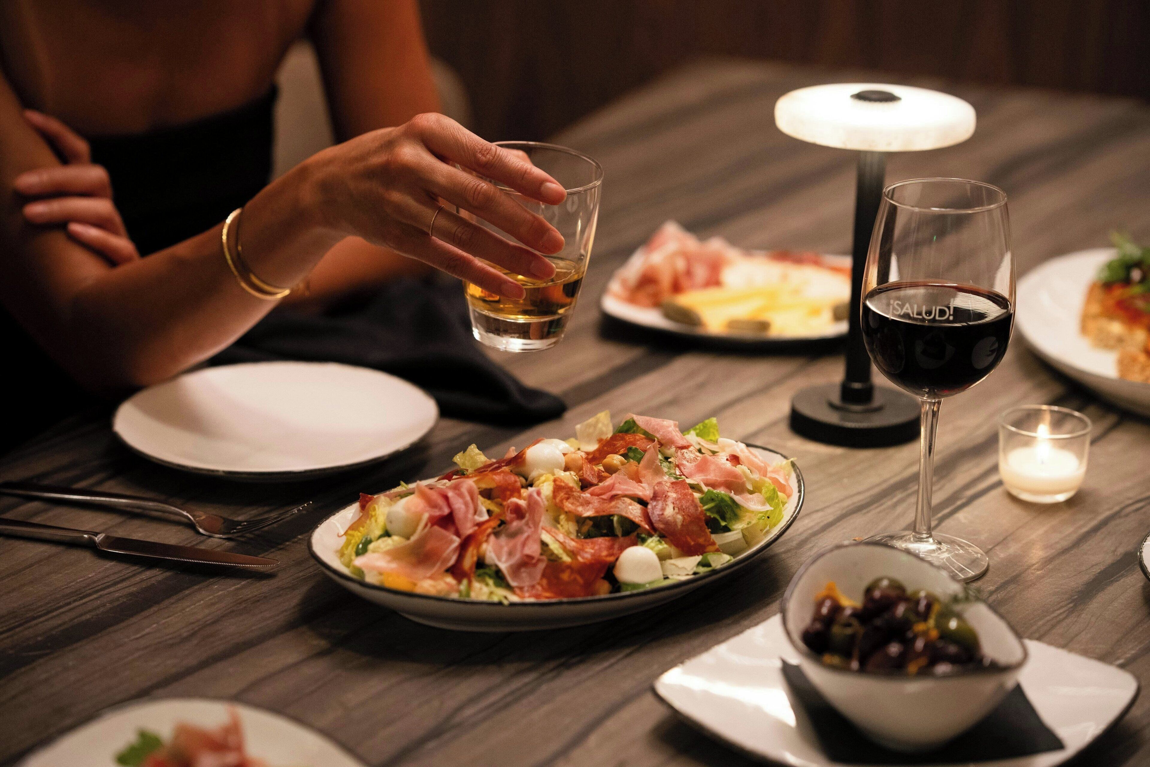 Un tavolo da pranzo con piatti di cibo, un bicchiere di vino rosso e una candela.