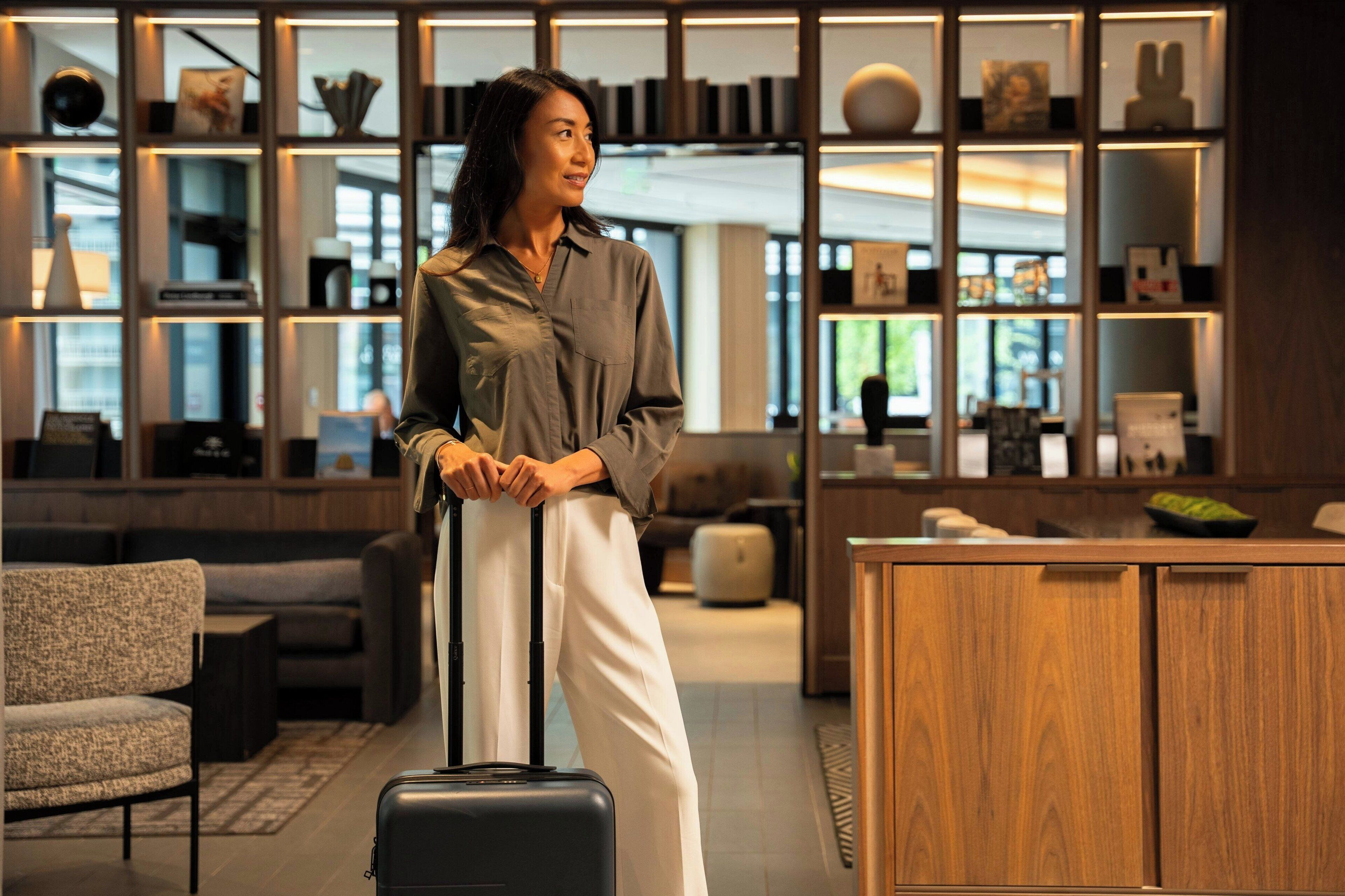 A modern hotel lobby with a seating area, a wooden cabinet, and a large window.