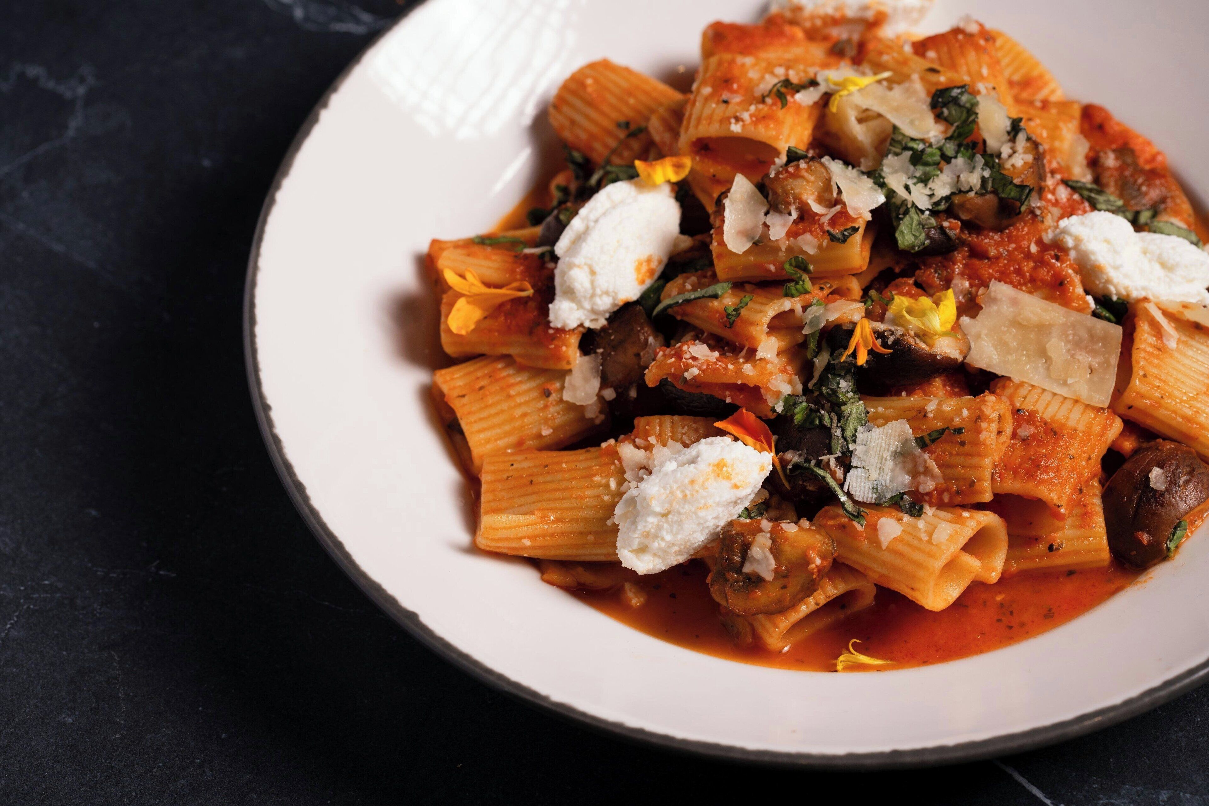A plate of pasta with a tomato-based sauce, topped with cheese and herbs.