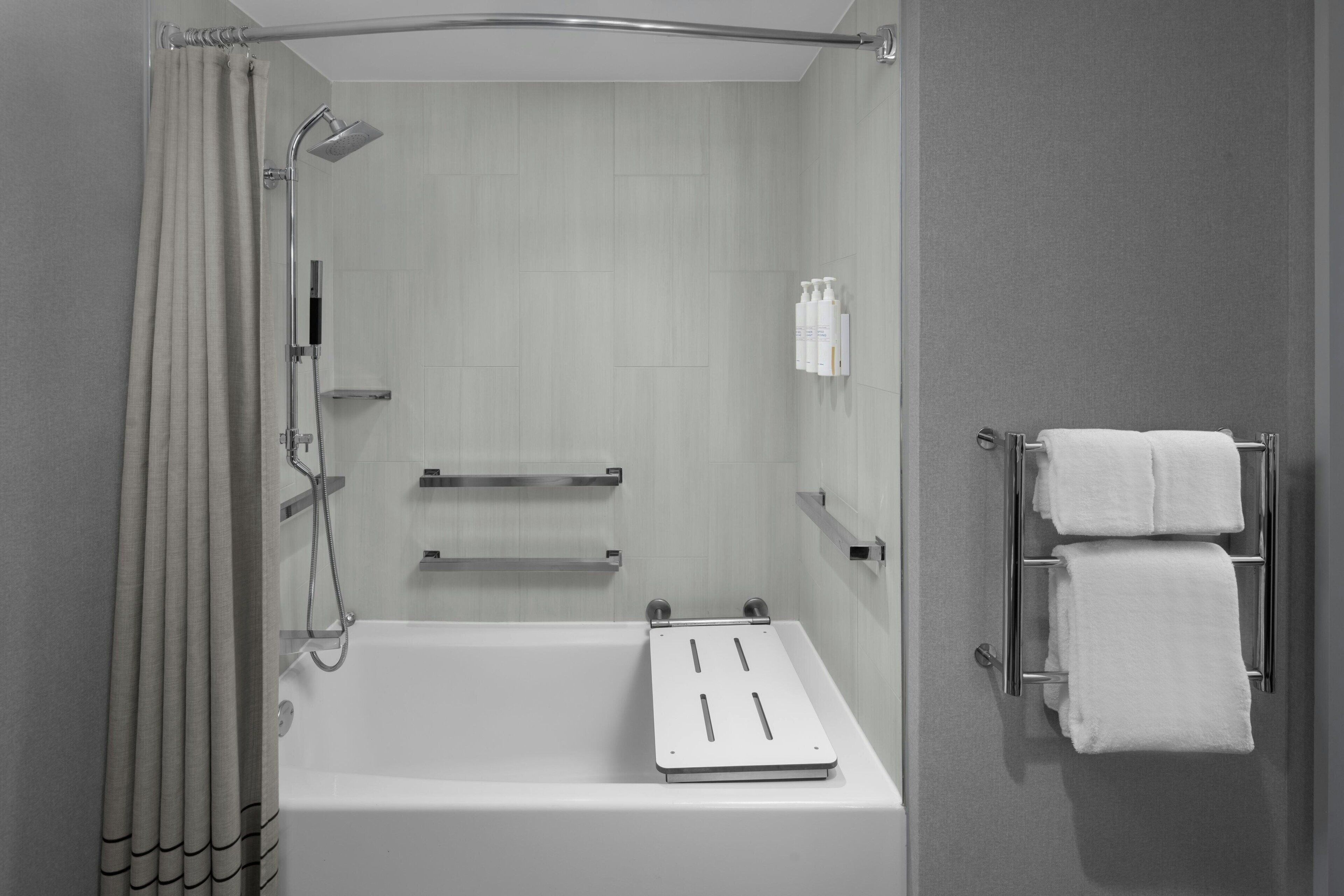 Un baño moderno con bañera, ducha, toallero y artículos de aseo.