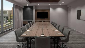 A conference room with a long table, multiple chairs, a large screen, and a city view.