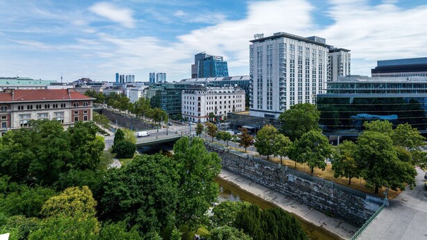 A cityscape with modern buildings, a river, and green spaces.