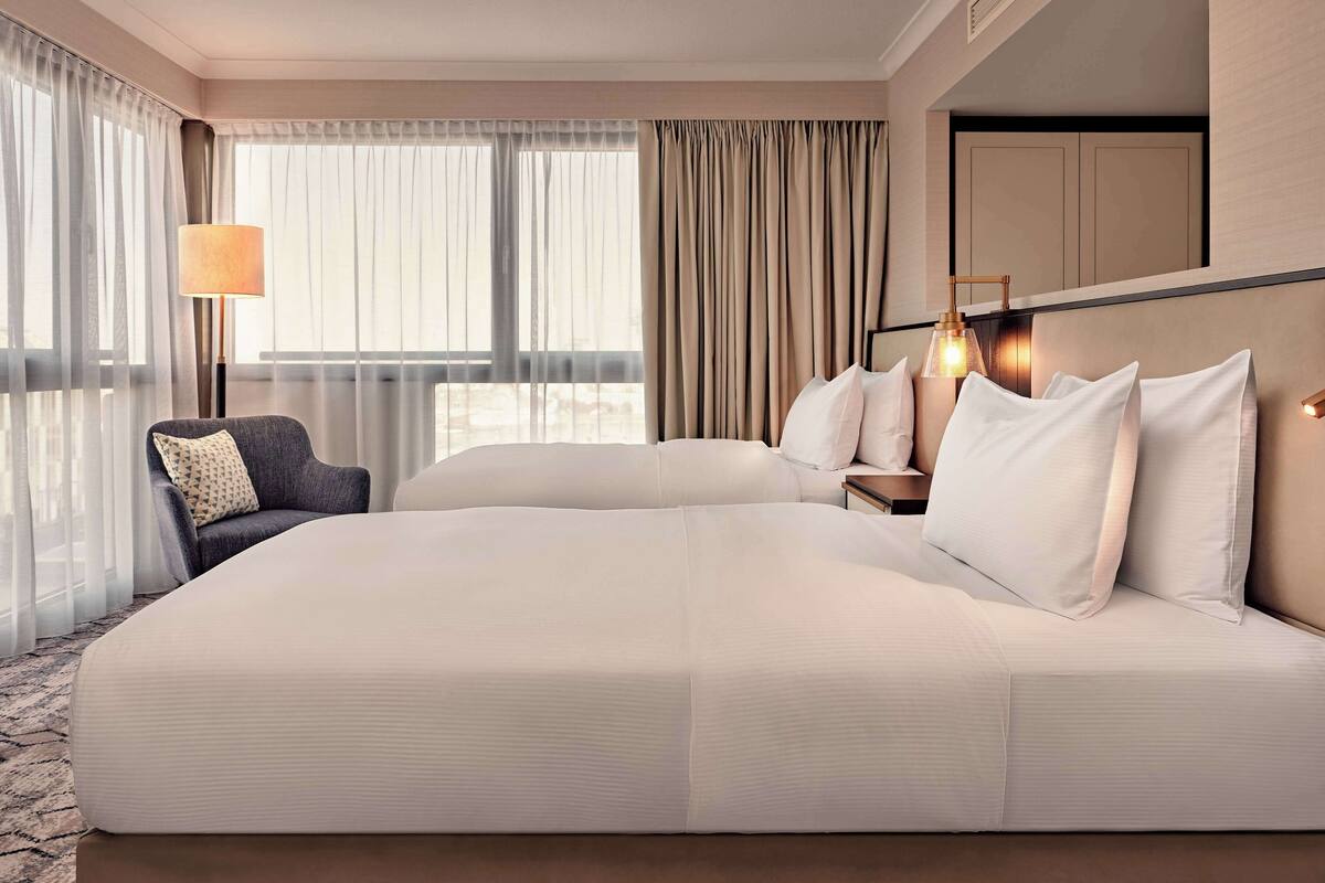 A hotel room with a large bed, a chair, a nightstand, and a lamp.