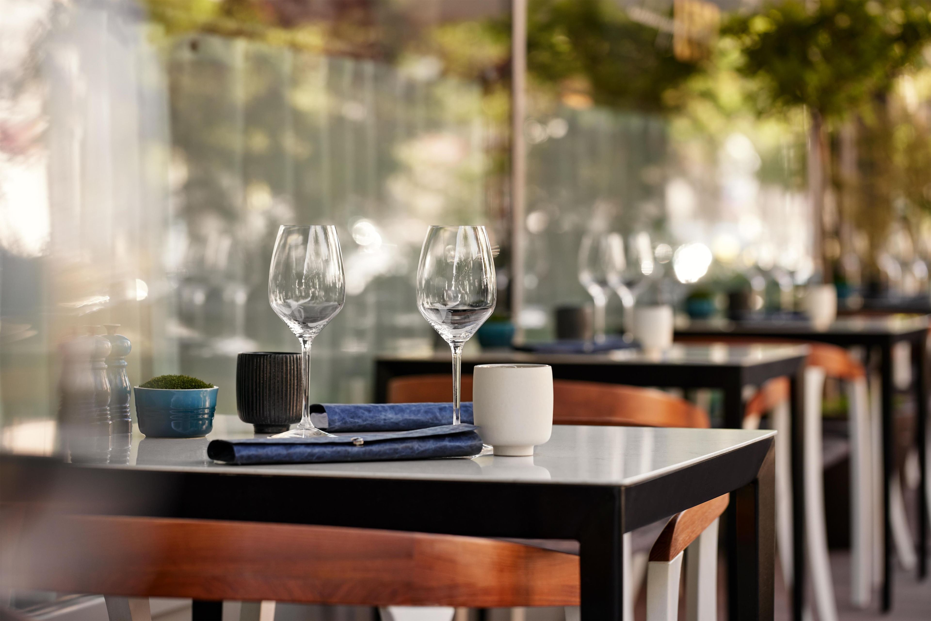 A table set with two wine glasses, a small bowl, a cup, and a napkin.