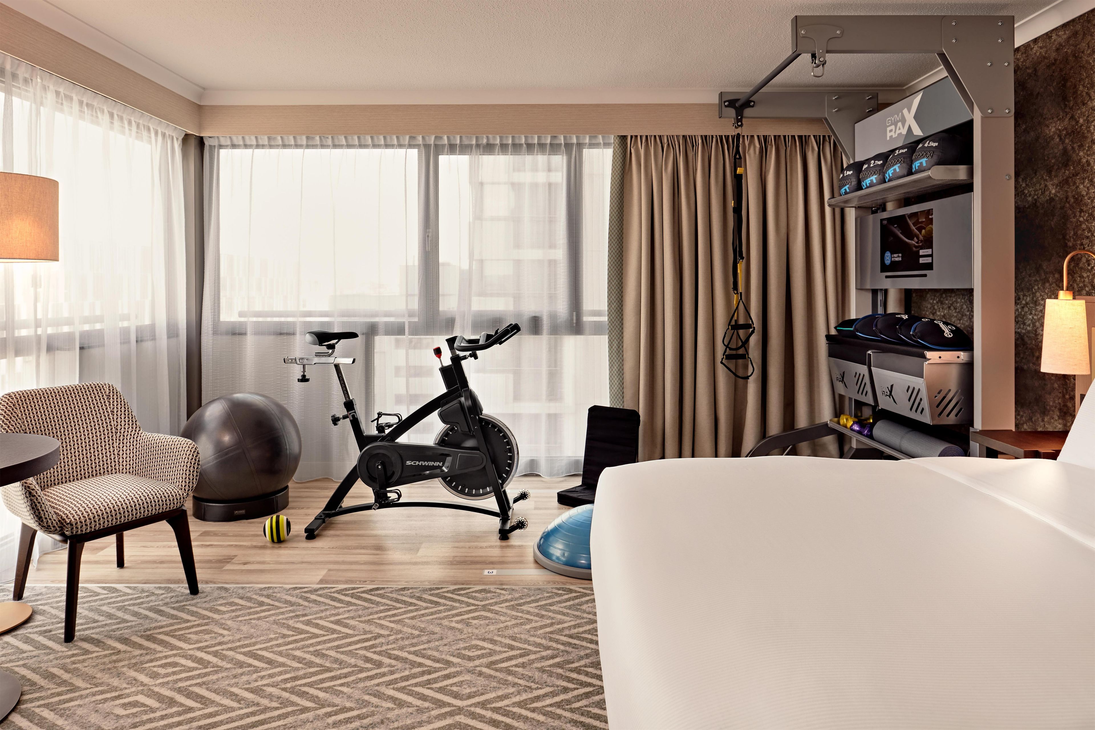 Ein Hotelzimmer mit Bett, Crosstrainer, Fitball und Fernseher.