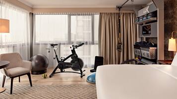 Ein Hotelzimmer mit Bett, Crosstrainer, Fitball und Fernseher.