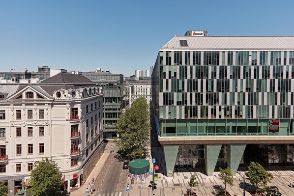 A modern building with large windows and a green awning. - Hilton Vienna Park (Vienna)