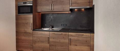 Una cocina moderna con armarios de madera, electrodomésticos de acero inoxidable y encimera negra.