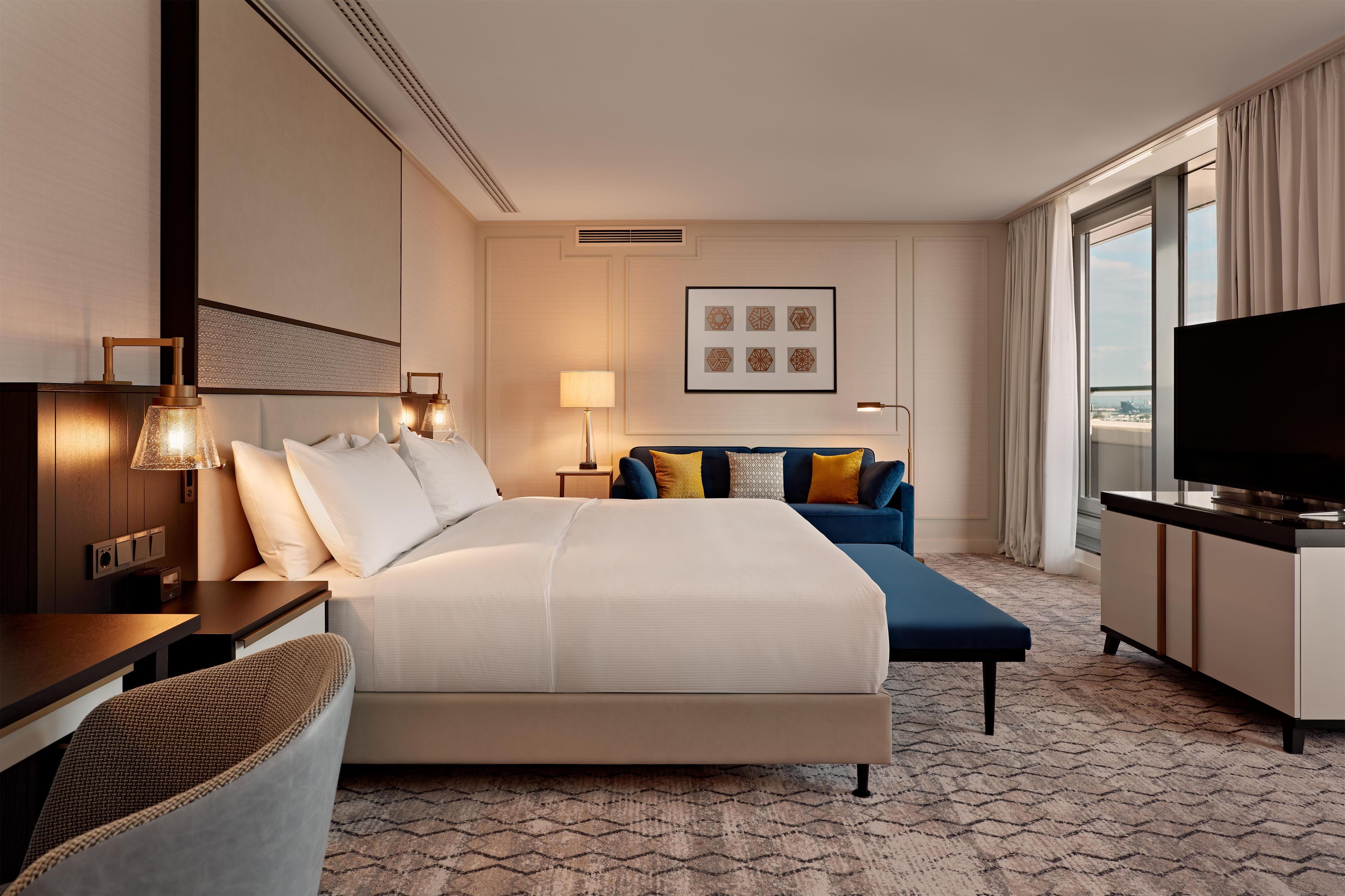 Camera d'albergo con un letto grande, una scrivania, un televisore e vista sulla città dalla finestra.