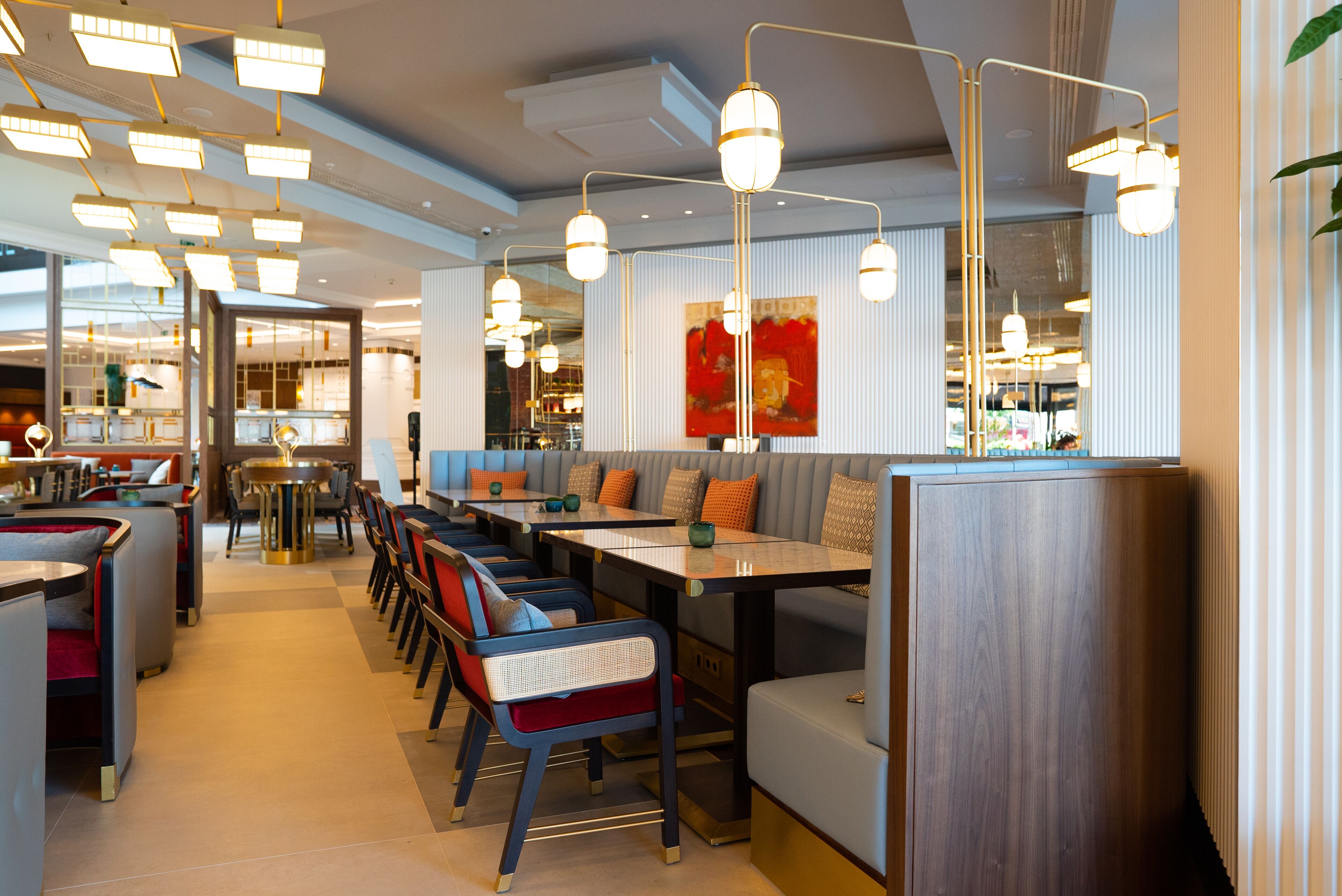 Un ristorante moderno con soffitti alti, illuminazione a sospensione e un mix di sedute a bancone e tavoli.