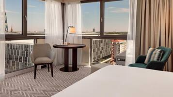 Ein Hotelzimmer mit großem Fenster, einem runden Tisch, zwei Stühlen und einem Bett.