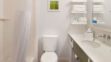 Un baño con inodoro, lavamanos y cortina de ducha.
