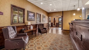 A lobby with a reception desk, two armchairs, a patterned carpet, and framed artwork on the walls. - Quality Inn Chickasha (Chickasha)