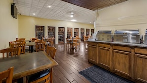 A restaurant with wooden flooring, multiple dining tables and chairs, and a buffet counter with stainless steel appliances. - Quality Inn Chickasha (Chickasha)