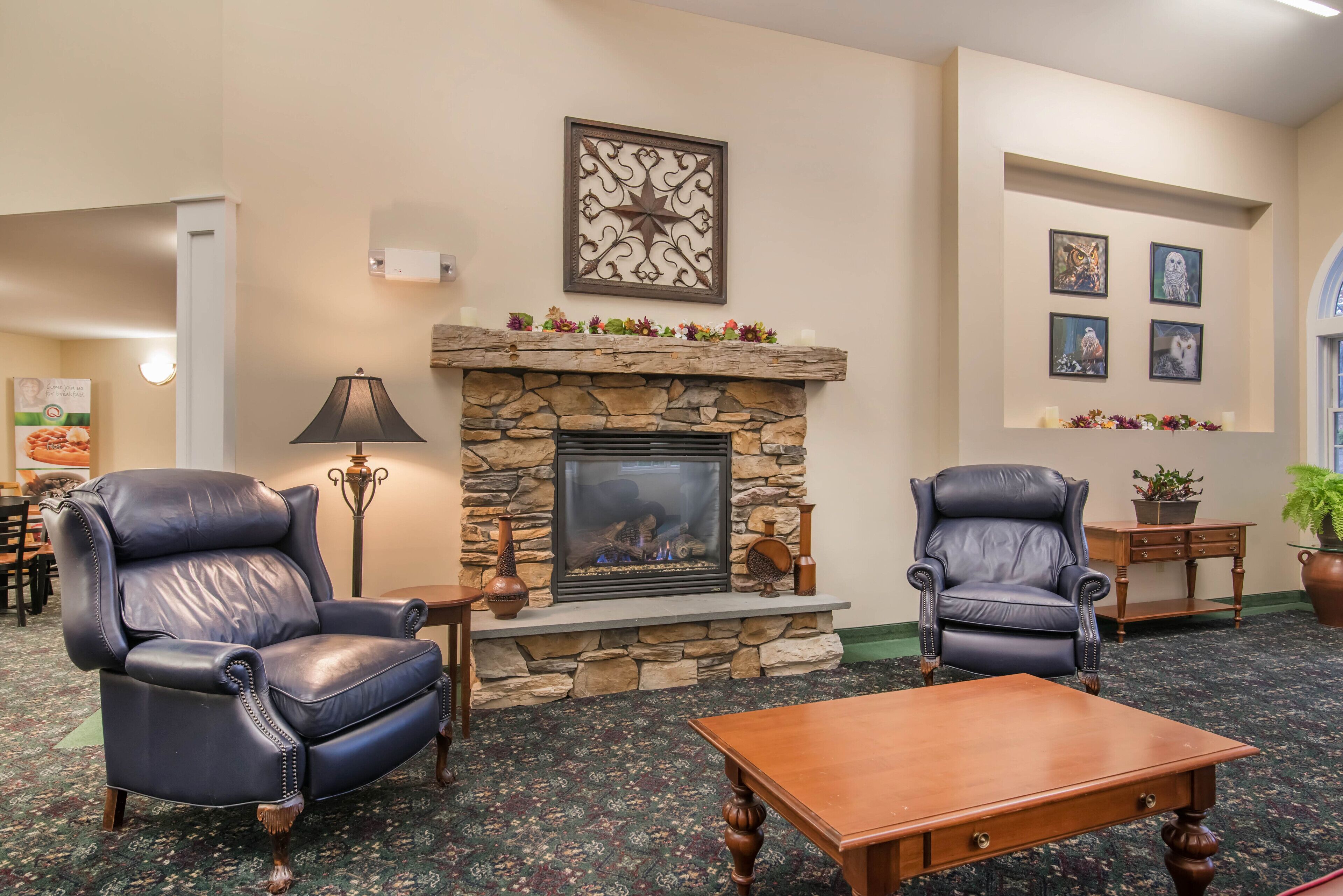 A cozy lounge area with a stone fireplace, leather armchairs, and a wooden coffee table.