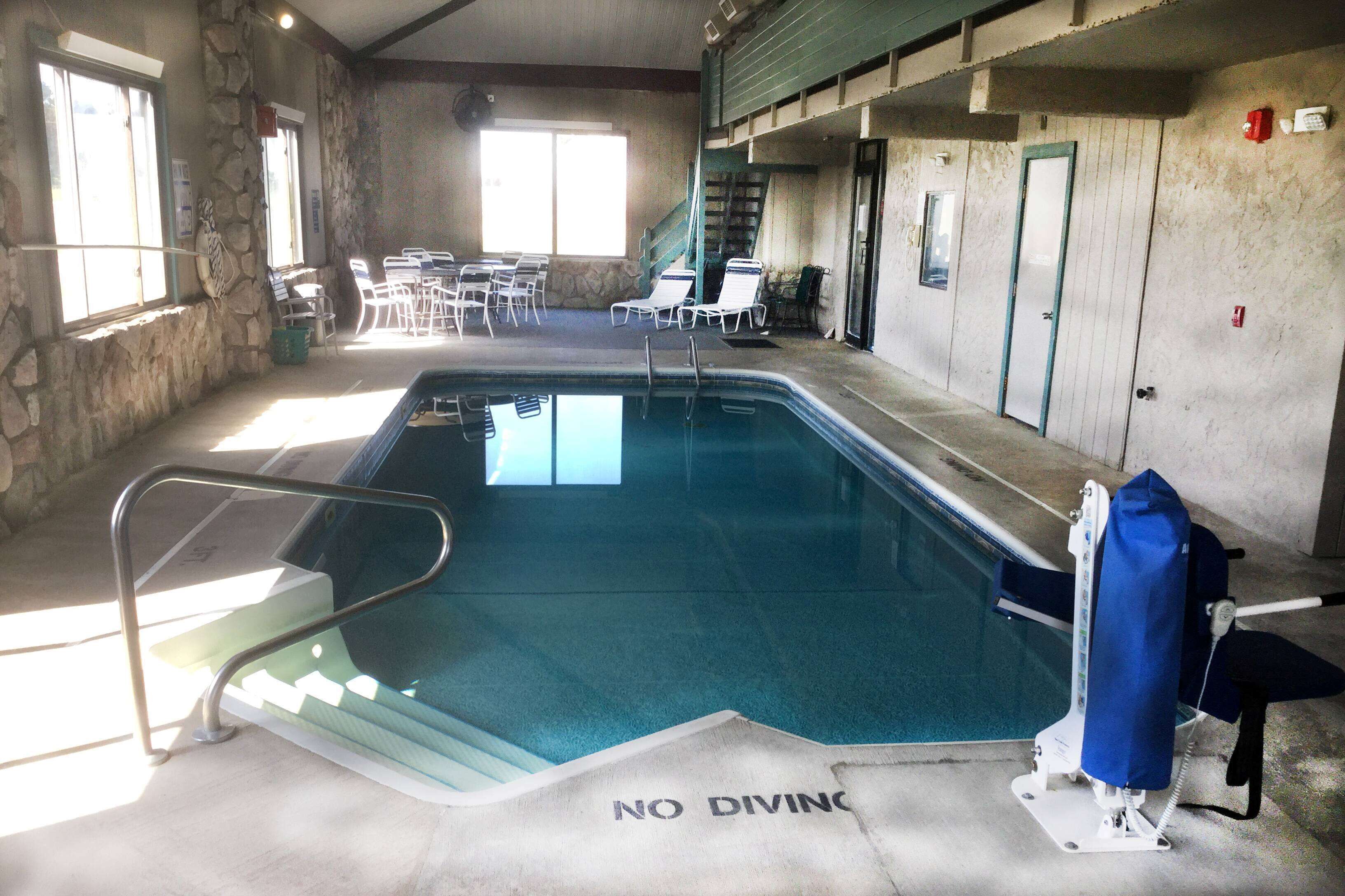 A swimming pool with a 'NO DIVING' sign, stone walls, and a staircase leading to an upper level.