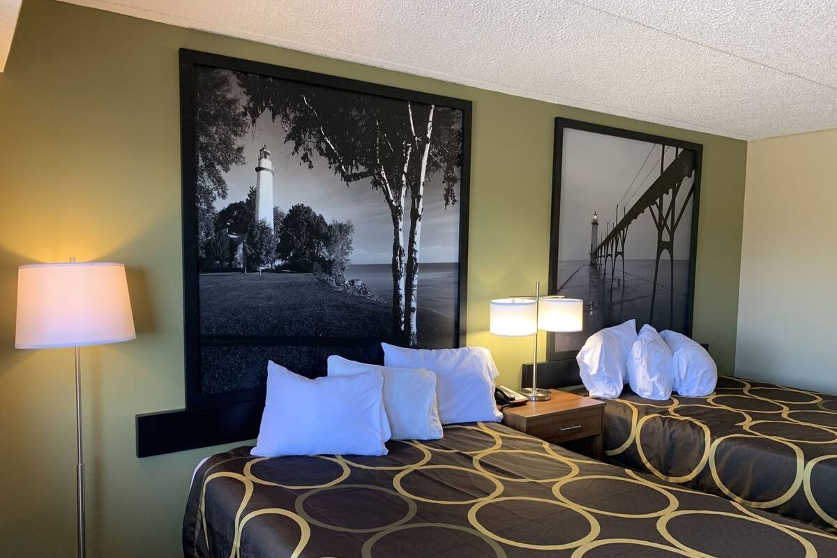 A hotel room with a bed, two bedside lamps, a nightstand, and two framed pictures on the wall.