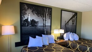 Habitación de hotel con dos camas, un cuadro grande con un faro y una lámpara a cada lado de la cama.