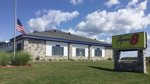 Un edificio de fachada de piedra, un asta con la bandera estadounidense y un letrero que dice "Super 8 by Wyndham".