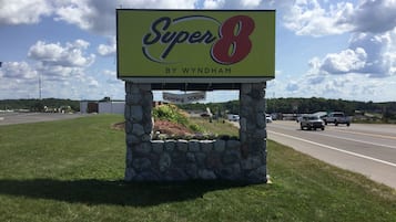 A Super 8 by Wyndham sign with a 'Coming Soon' message, set against a backdrop of a road and a clear sky.