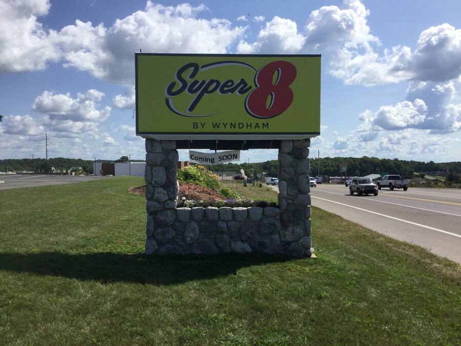 A Super 8 by Wyndham sign with a 'Coming Soon' message, set against a backdrop of a road and a clear sky.